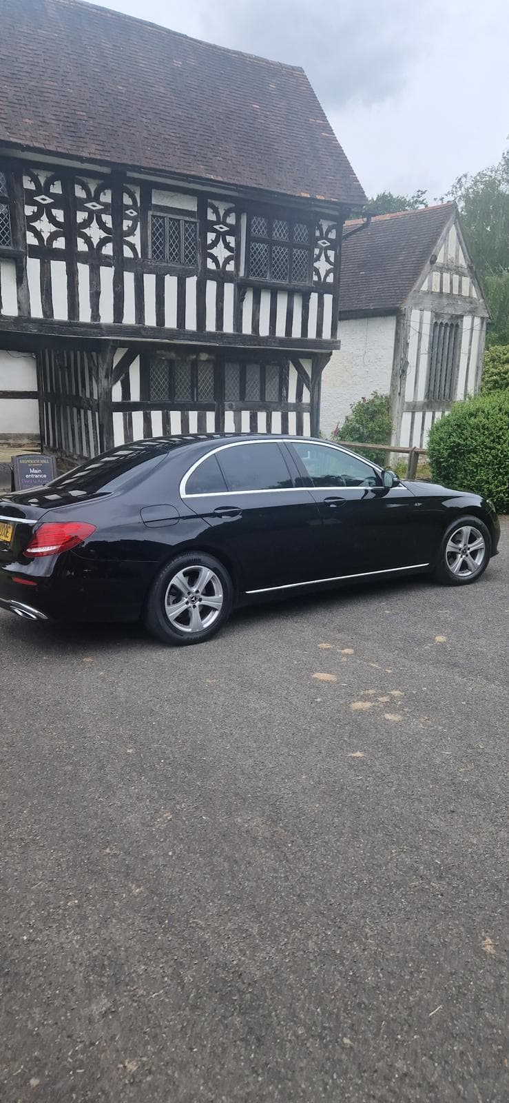 Black executive saloon outside a timber-framed building